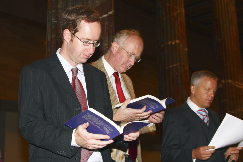 Drei Veranstaltungsteilnehmer blättern in dem vorgestellten Buch.