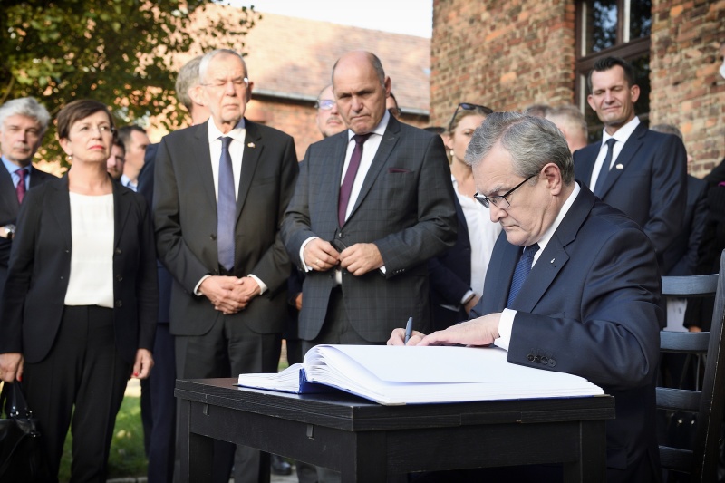 Vizepremierminister Polens Piotr Gliński beim Eintrag ins Gästebuch vor Block 17