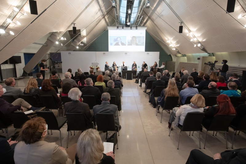 Blick in den Saal Richtung Bühne. Am Podium von links: Moderator Universitätsprofessor Florian Bieber, Universität Graz, Nationalratsabgeordnete Ewa Ernst-Dziedzic (GRÜNE), Nationalratsabgeordnete Bedrana Ribo (GRÜNE), Nationalratsabgeordnete Carmen Jeitler-Cincelli (ÖVP), Nationalratsabgeordnete Eva Blimlinger (GRÜNE), Nationalratsabgeordnete Gudrun Kugler (ÖVP), Moderatorin Aleksandra Tomanic. Zugeschaltet auf der Leinwand von links: Bundesrat Christian Buchmann (ÖVP), Professor Damir Kapidžić, Universität Sarajewo