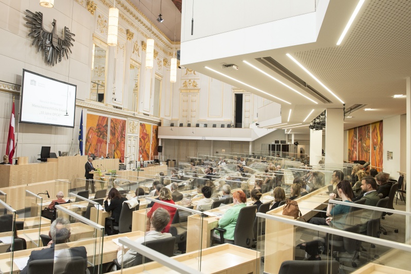 Blick Richtung Veranstaltungsteilnehmer:innen. Am Rednerpult: Volksanwalt Walter Rosenkranz