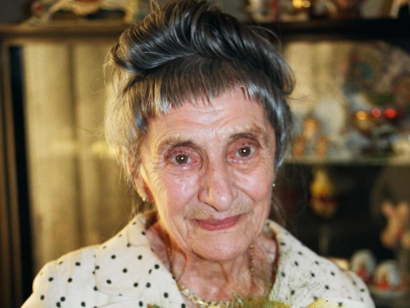 Portraitfoto von Margaretha Lupac. Sie hat graue Haare, die hochgesteckt sind, und trägt einen weißen Blazer mit schwarzen Punkten.