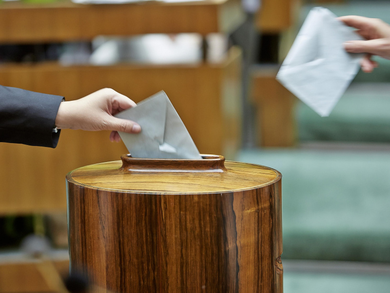 Die Abgeordneten werfen die ausgefüllten Stimmzettel in eine Wahlurne. 