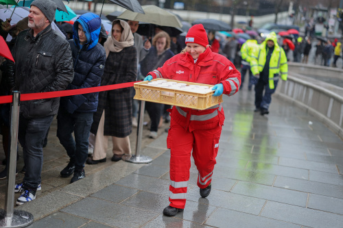 Ausgabe von Tee an die wartenden Besucher bei strömendem Regen durch Mitarbieter des Roten Kreuzes