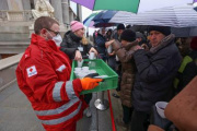 Ausgabe von Tee an die wartenden Besucher bei strömendem Regen durch Mitarbieter des Roten Kreuzes