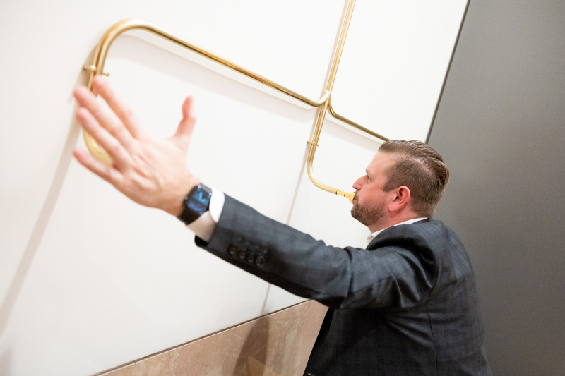 Ein Veranstaltungsteilnehmer probiert das Kunstwerk "Demokratietrompete" aus