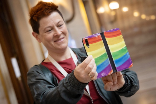 Veranstaltungsteilnehmerin mit Handy in LGBTIQ Farben