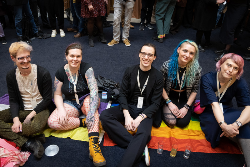 Veranstaltungsteilnehmer:innen auf Nicht-Binär-Fahne sitzend