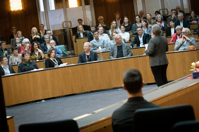 Anmoderation Daniela Kraus. Blick Richtung Veranstaltungsteilnehmer:innen