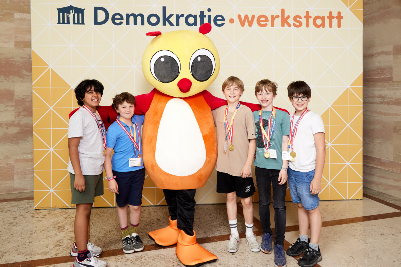 Fotopoint mit den Maskottchen der Demkratiewerkstatt und Schüler:innen