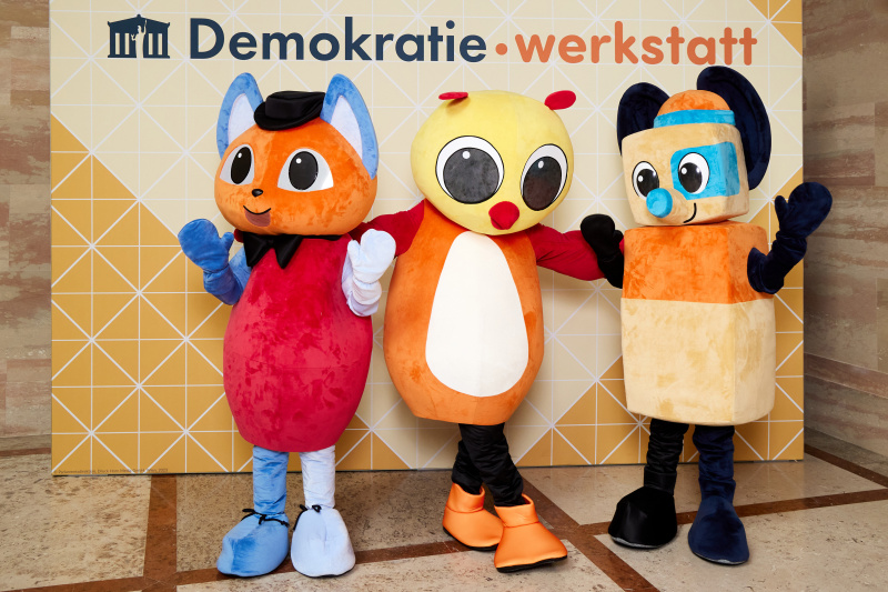 Fotopoint mit den Maskottchen der Demkratiewerkstatt und Schüler:innen