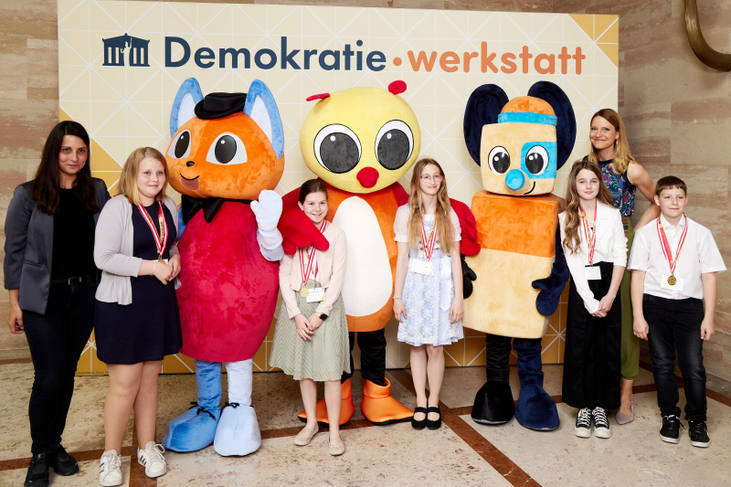 Fotopoint mit den Maskottchen der Demkratiewerkstatt und Schüler:innen