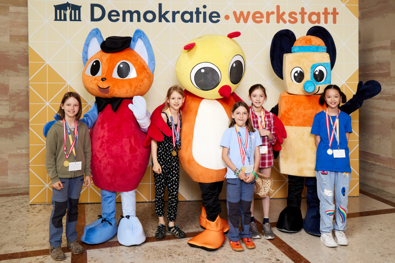 Fotopoint mit den Maskottchen der Demkratiewerkstatt und Schüler:innen