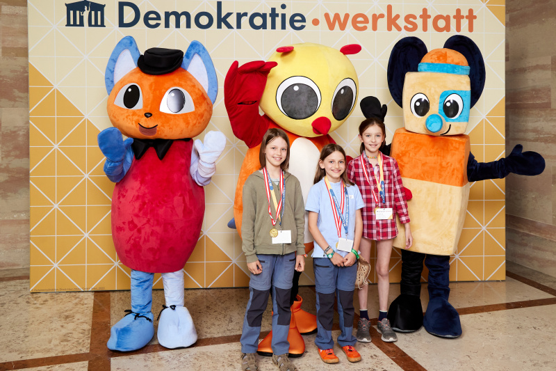 Fotopoint mit den Maskottchen der Demkratiewerkstatt und Schüler:innen