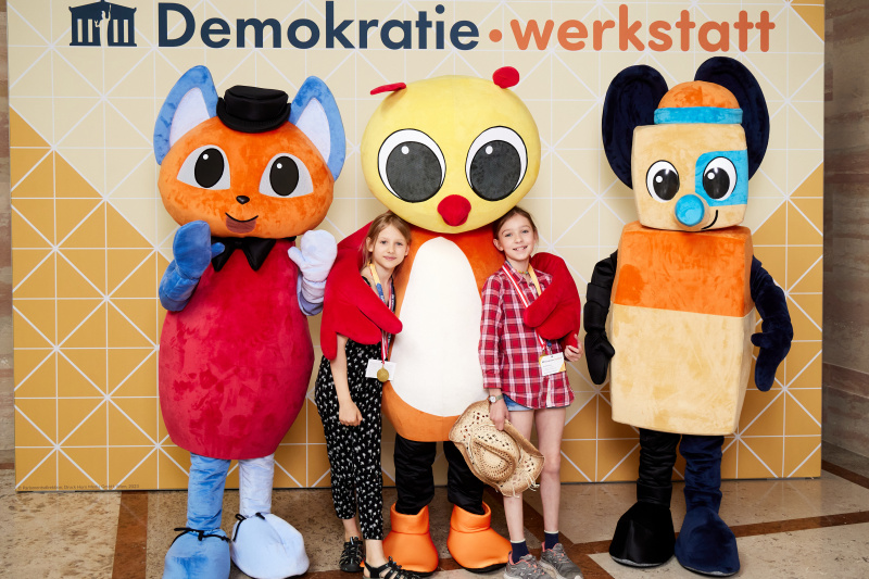 Fotopoint mit den Maskottchen der Demkratiewerkstatt und Schüler:innen