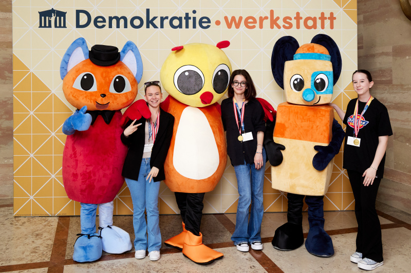 Fotopoint mit den Maskottchen der Demkratiewerkstatt und Schüler:innen