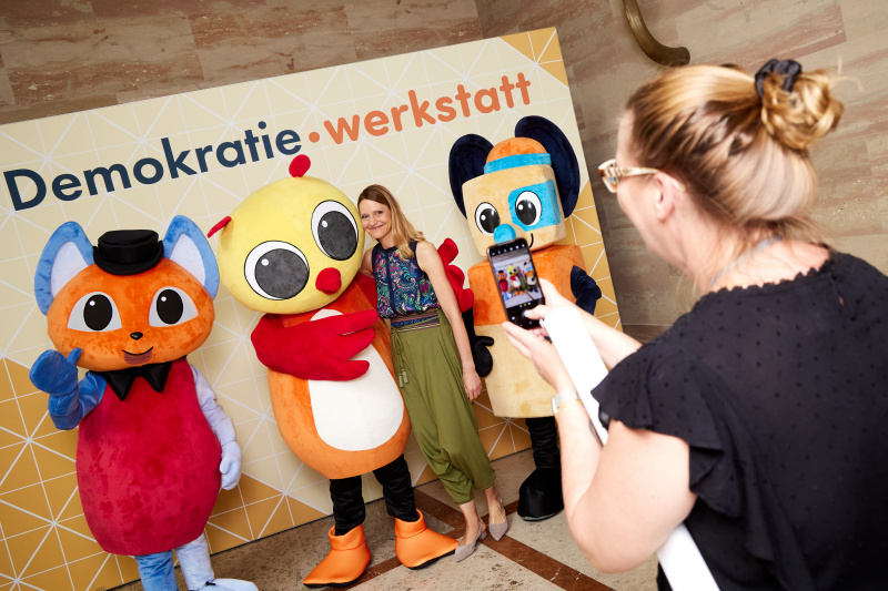 Fotopoint mit den Maskottchen der Demkratiewerkstatt und Schüler:innen