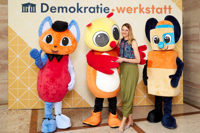Fotopoint mit den Maskottchen der Demkratiewerkstatt und Schüler:innen