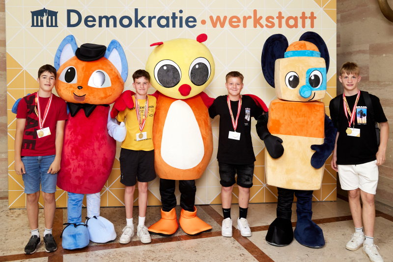 Fotopoint mit den Maskottchen der Demkratiewerkstatt und Schüler:innen
