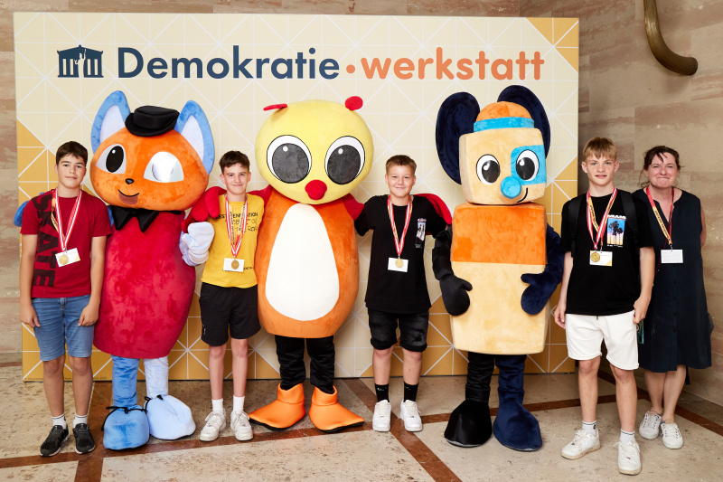 Fotopoint mit den Maskottchen der Demkratiewerkstatt und Schüler:innen