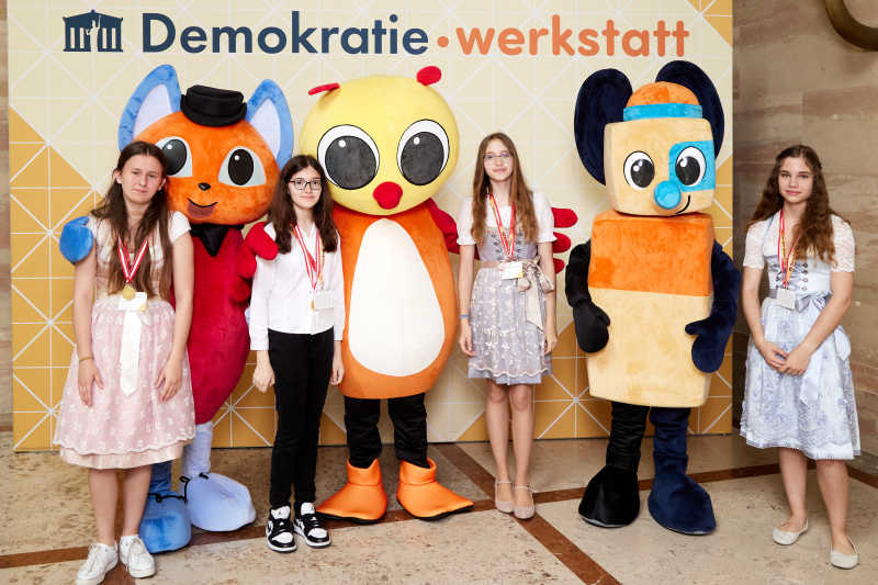Fotopoint mit den Maskottchen der Demkratiewerkstatt und Schüler:innen