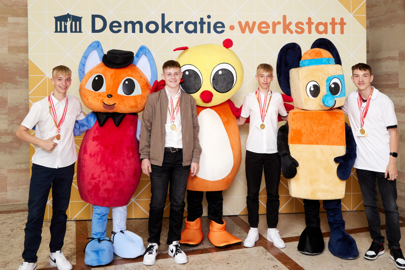 Fotopoint mit den Maskottchen der Demkratiewerkstatt und Schüler:innen