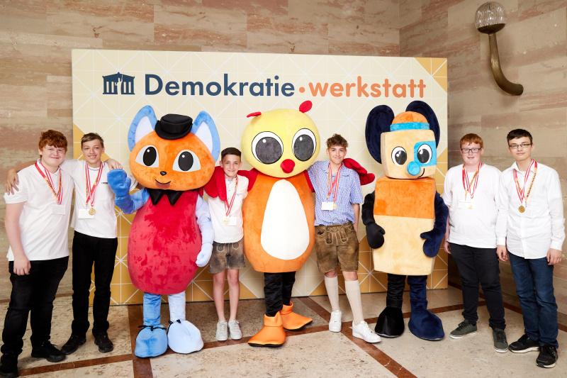 Fotopoint mit den Maskottchen der Demkratiewerkstatt und Schüler:innen