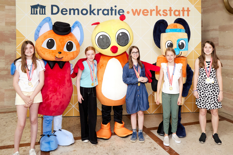 Fotopoint mit den Maskottchen der Demkratiewerkstatt und Schüler:innen