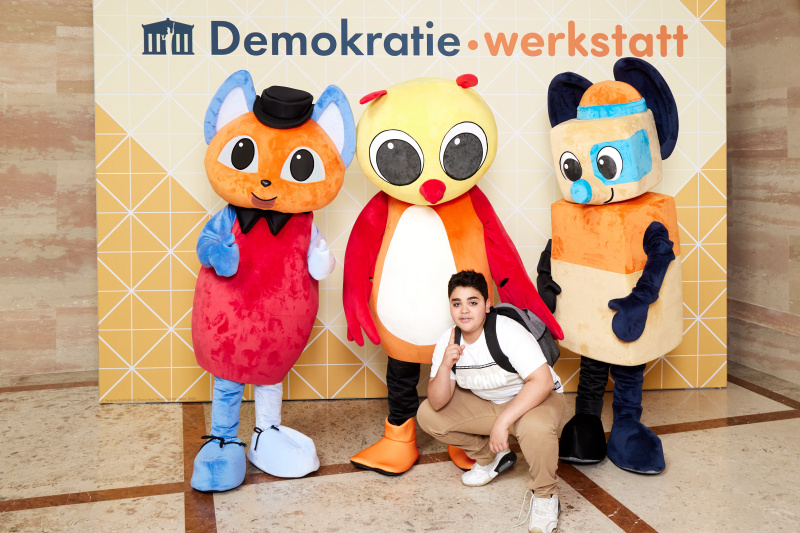 Fotopoint mit den Maskottchen der Demkratiewerkstatt und Schüler:innen