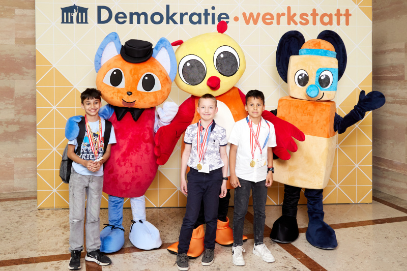 Fotopoint mit den Maskottchen der Demkratiewerkstatt und Schüler:innen