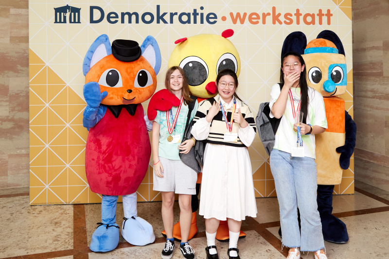 Fotopoint mit den Maskottchen der Demkratiewerkstatt und Schüler:innen