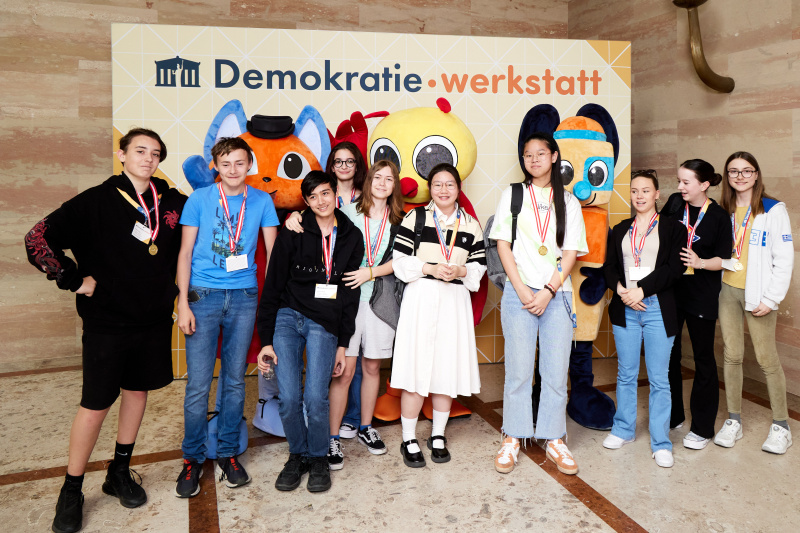 Fotopoint mit den Maskottchen der Demkratiewerkstatt und Schüler:innen