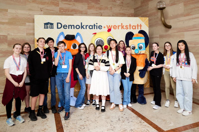 Fotopoint mit den Maskottchen der Demkratiewerkstatt und Schüler:innen