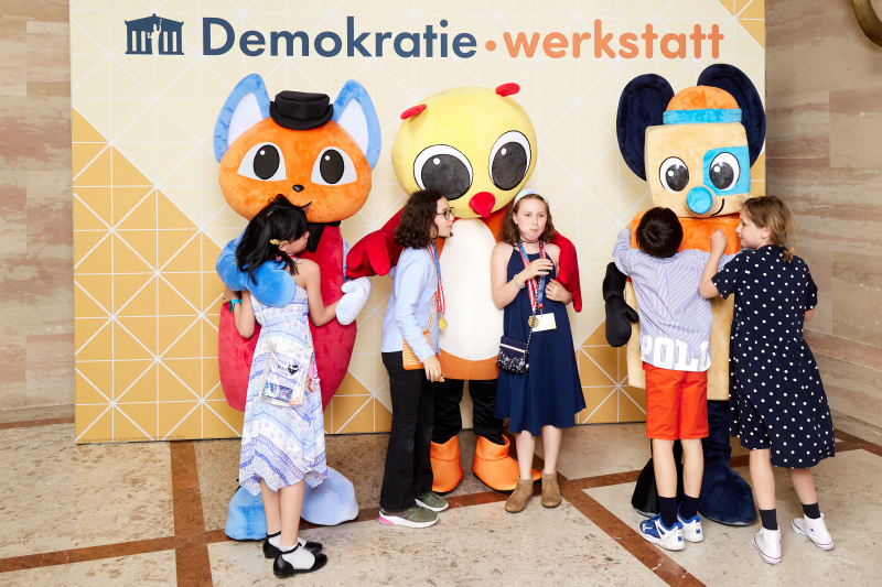 Fotopoint mit den Maskottchen der Demkratiewerkstatt und Schüler:innen