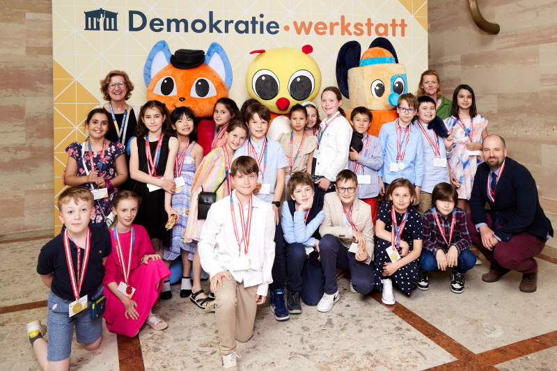 Fotopoint mit den Maskottchen der Demkratiewerkstatt und Schüler:innen