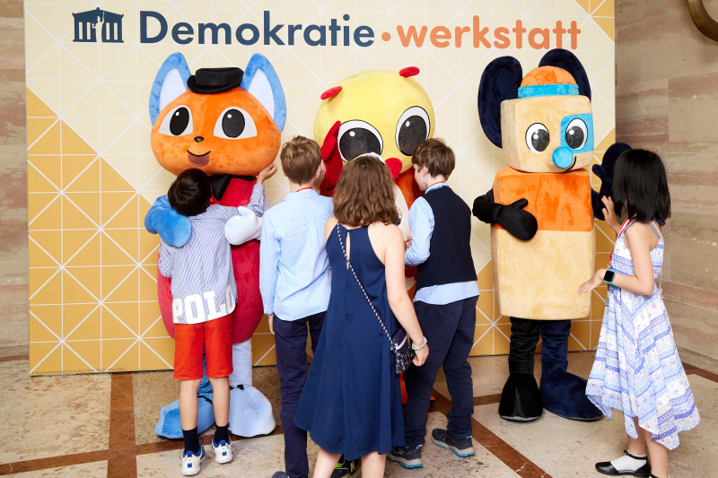 Fotopoint mit den Maskottchen der Demkratiewerkstatt und Schüler:innen