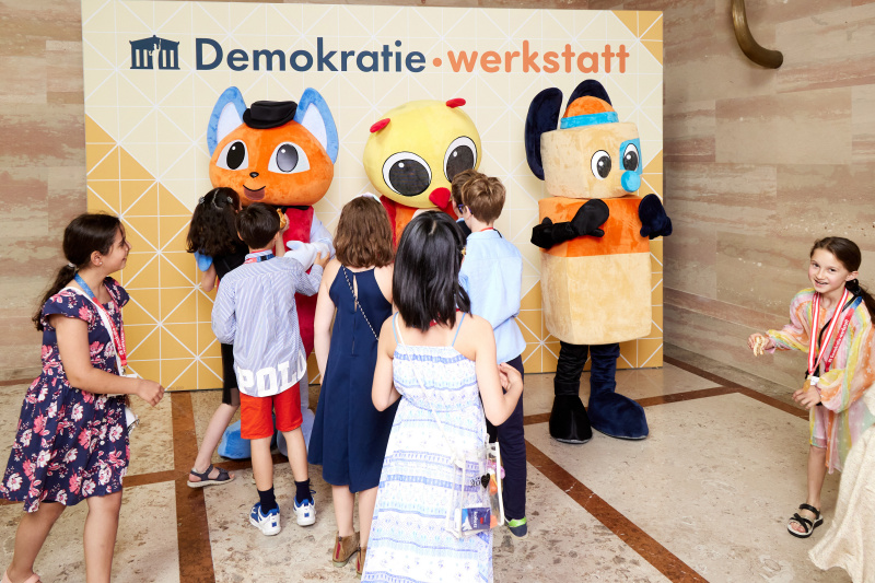Fotopoint mit den Maskottchen der Demkratiewerkstatt und Schüler:innen