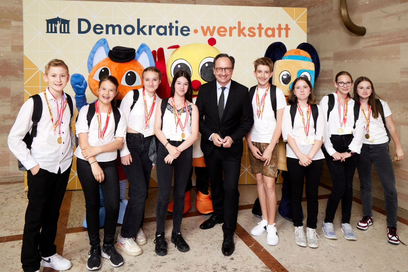 Fotopoint mit den Maskottchen der Demkratiewerkstatt und Schüler:innen