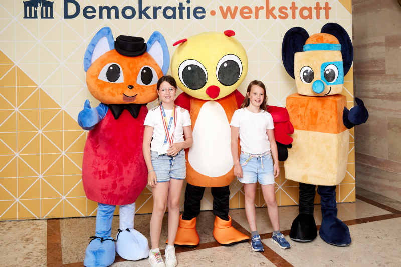 Fotopoint mit den Maskottchen der Demkratiewerkstatt und Schüler:innen