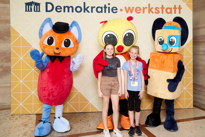 Fotopoint mit den Maskottchen der Demkratiewerkstatt und Schüler:innen
