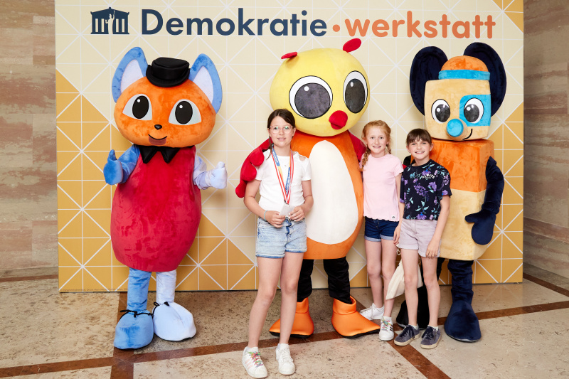 Fotopoint mit den Maskottchen der Demkratiewerkstatt und Schüler:innen