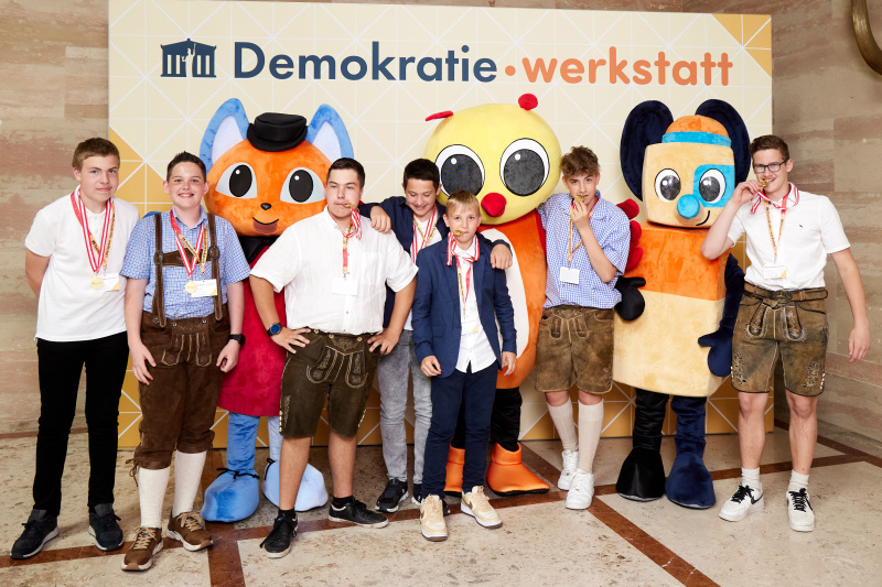Fotopoint mit den Maskottchen der Demkratiewerkstatt und Schüler:innen