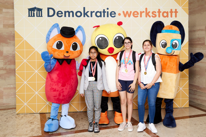 Fotopoint mit den Maskottchen der Demkratiewerkstatt und Schüler:innen
