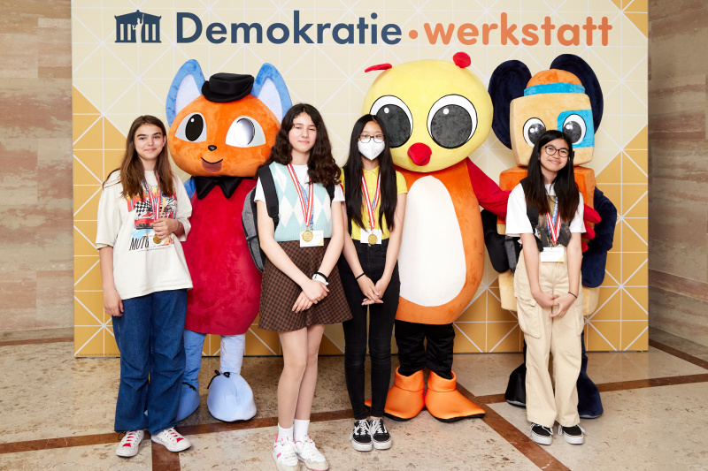 Fotopoint mit den Maskottchen der Demkratiewerkstatt und Schüler:innen