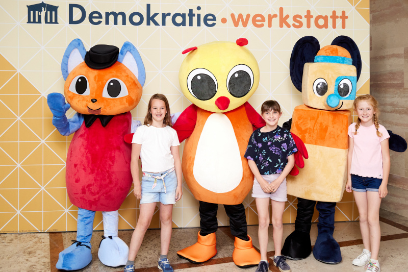 Fotopoint mit den Maskottchen der Demkratiewerkstatt und Schüler:innen