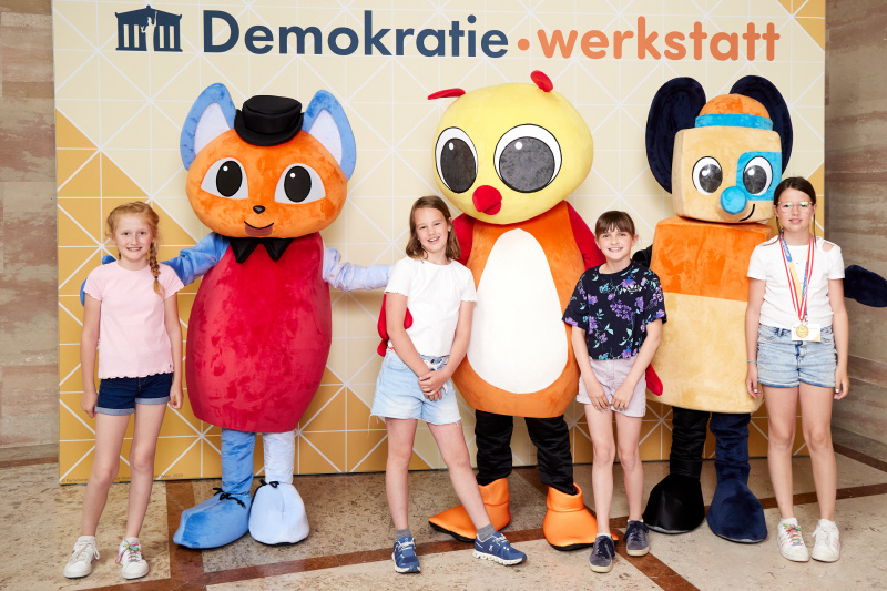 Fotopoint mit den Maskottchen der Demkratiewerkstatt und Schüler:innen