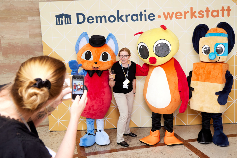 Fotopoint mit den Maskottchen der Demkratiewerkstatt und Schüler:innen