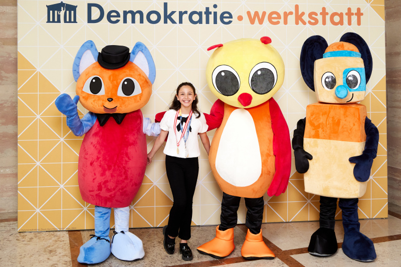 Fotopoint mit den Maskottchen der Demkratiewerkstatt und Schüler:innen