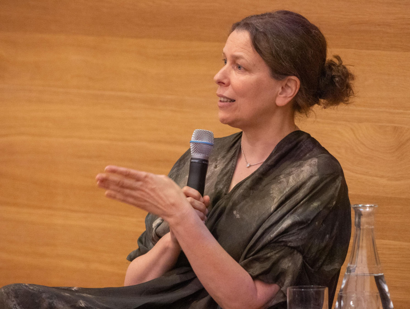 Iris Eisenberger sitzt am Podium und spricht ins Mikrofon.