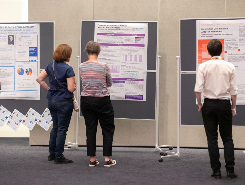 3 Personen stehen vor 3 Pinnwänden und sehen sich die ausge-stellten wissenschaftlichen Poster an.