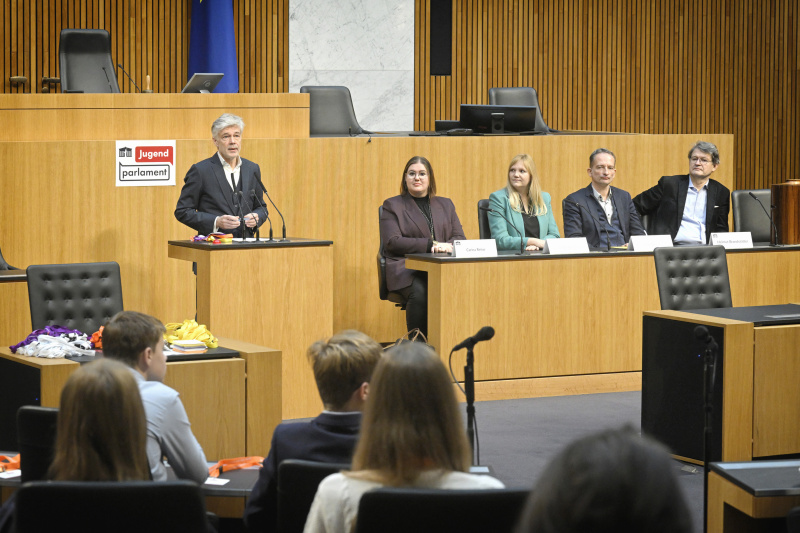Begrüßung. Am Rednerpult Parlamentsdirektor Harald Dossi. Regierungsbank von links: Nationalratsabgeordnete Carina Reiter (ÖVP), Nationalratsabgeordnete Elisabeth Feichtinger (SPÖ), Nationalratsabgeordneter Hermann Weratschnig (GRÜNE), Nationalratsabgeordneter Helmut Brandstätter (NEOS)